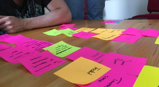 A person looking at a table covered in colourful post-it notes