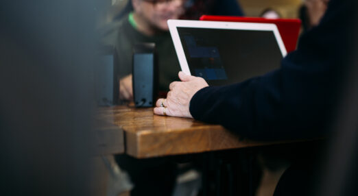 A person using a tablet, with other people in the background.
