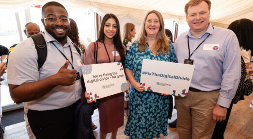 Four people at an event holding signs that say Fix The Digital Divide